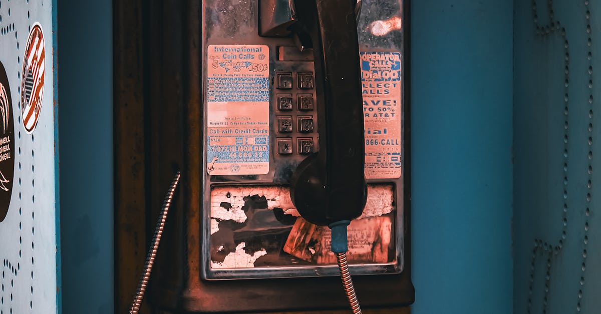Close-up of a vintage pay phone, showcasing unique wear and retro style in an urban environment.