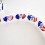Close-up of a roll of 'I Voted' stickers featuring the American flag design on a white background.