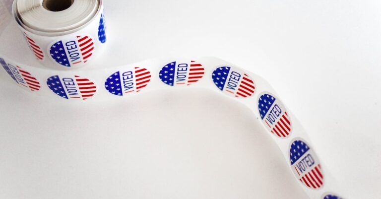 Close-up of a roll of 'I Voted' stickers featuring the American flag design on a white background.