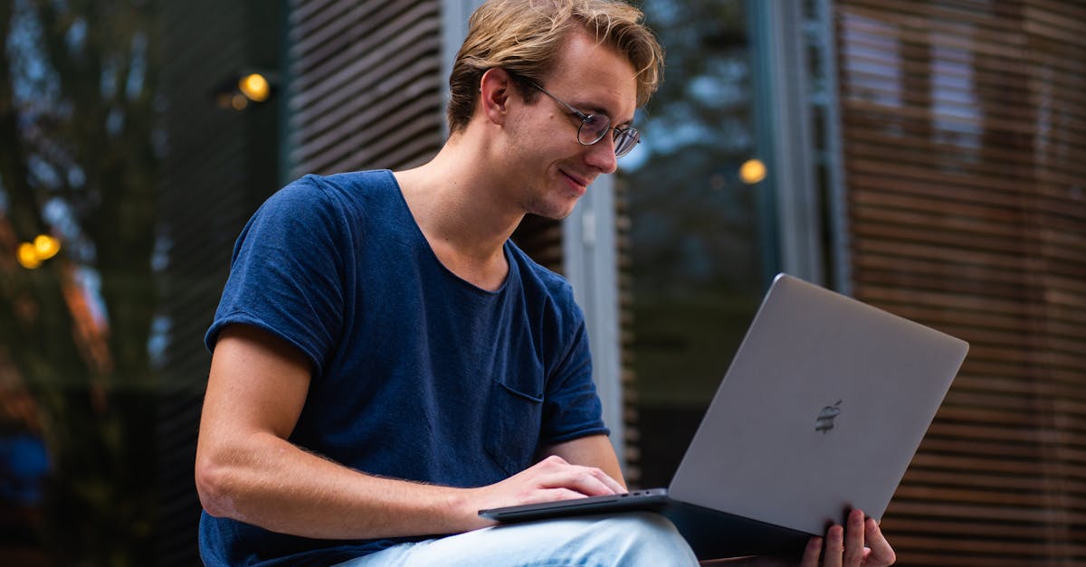 A young man sitting outdoors in Leiden, Netherlands, working on a laptop.