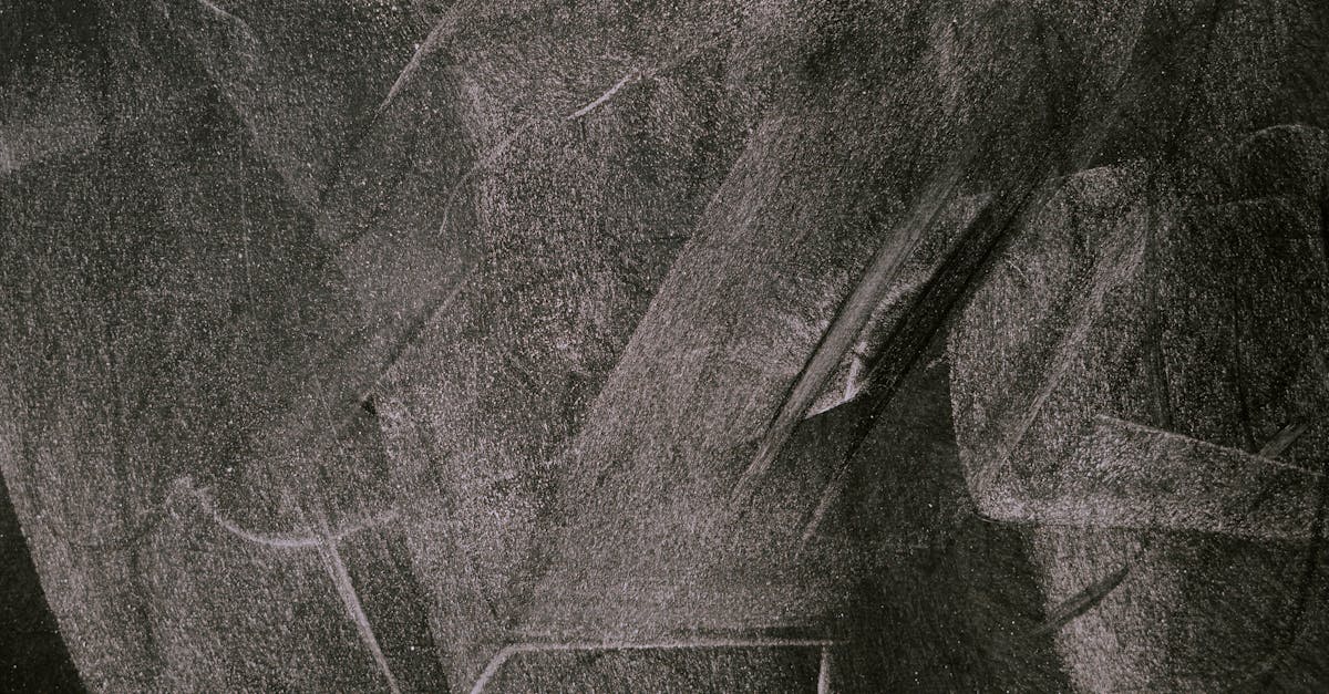 Abstract art showcasing smudged white chalk patterns on a blackboard, capturing texture and form.