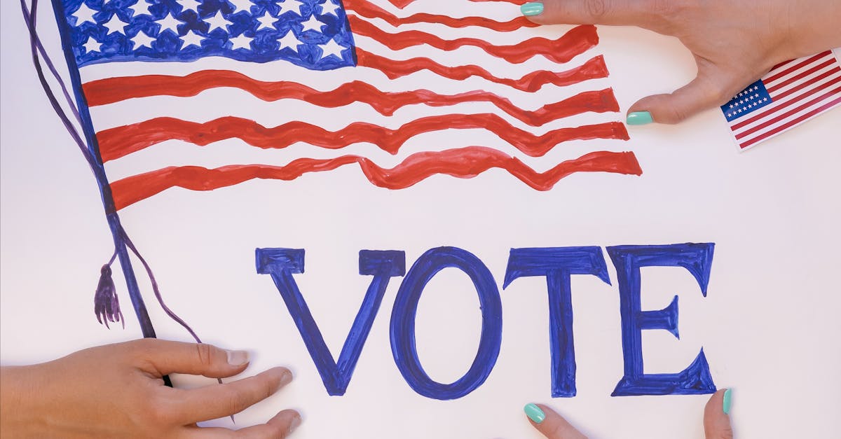 Hands arranging a patriotic voting poster with American flags, encouraging civic participation.