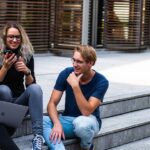 Three young professionals having a friendly chat while sitting on outdoor steps.