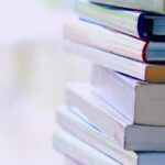 A tall stack of colorful hardcover books on a table indoors, perfect for library-themed concepts.