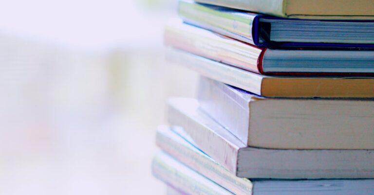 A tall stack of colorful hardcover books on a table indoors, perfect for library-themed concepts.