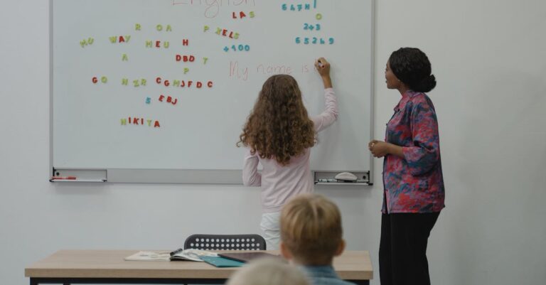 Teacher instructing diverse students with magnetic letters on a classroom whiteboard.