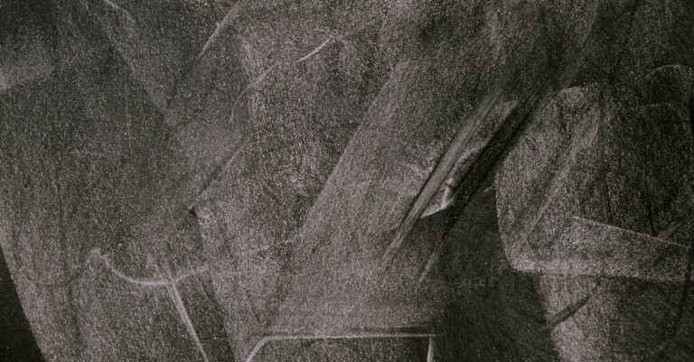 Abstract art showcasing smudged white chalk patterns on a blackboard, capturing texture and form.