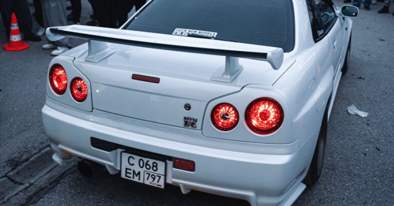 A dynamic scene of a white sports car at a car meet in Ankara, with a crowd observing.